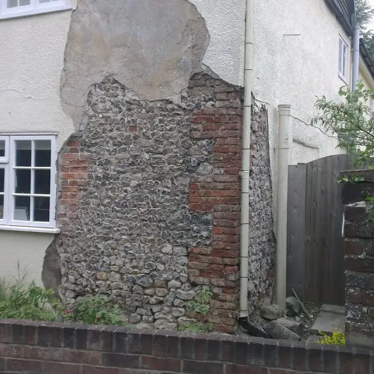 Flint and brick wall uncovered after failed cement render was removed