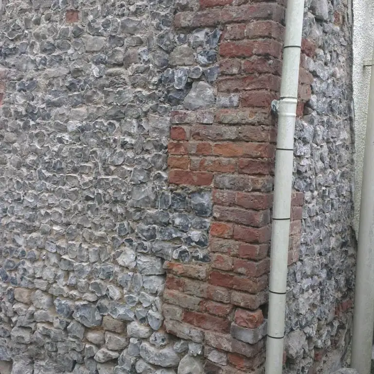 Flint and brick wall uncovered after failed cement render was removed