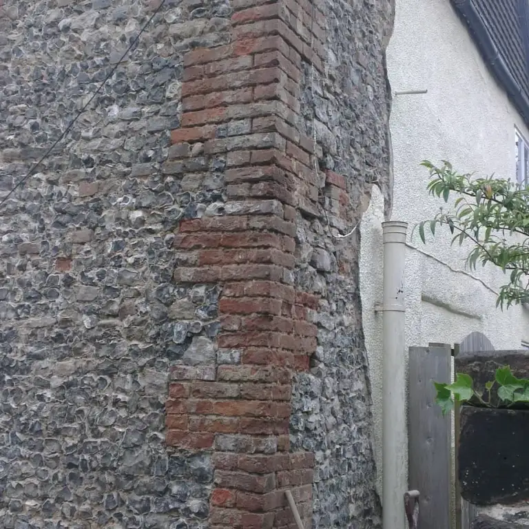 Flint and brick wall uncovered after failed cement render was removed