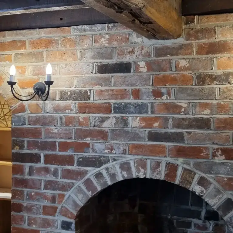 Fireplace opening with reclaimed timber beam and lime-hemp plaster finish