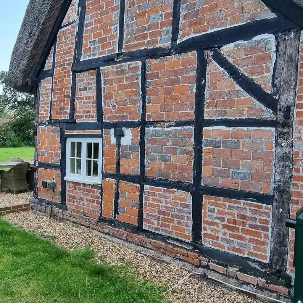 Timber-framed house with brick infill panels removed ready for new timbers