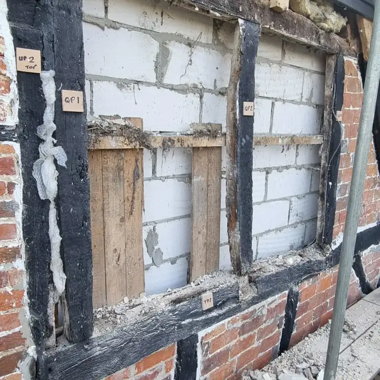 Timber-framed house with brick infill panels removed ready for new timbers