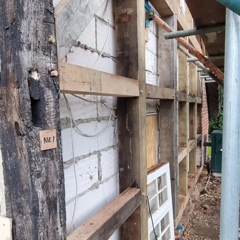 Timber-framed house with brick infill panels removed ready for new timbers